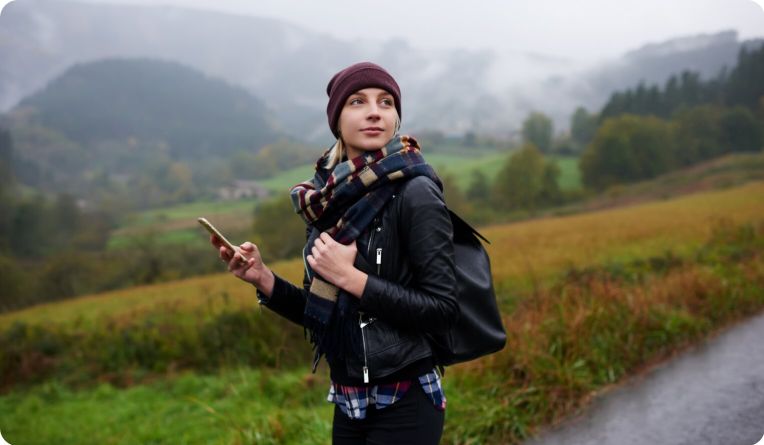 Woman with phone in hand walking on a road