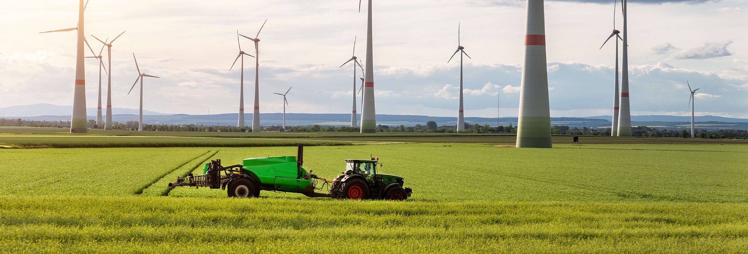 Picture of tractor driving over a fields with windmills in background