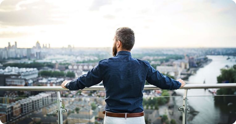 Man standing on a balcony looking at a city view